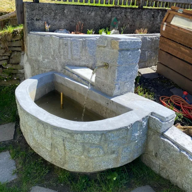 Neu gebauter Granitbrunnen mit fließendem Wasser im Garten